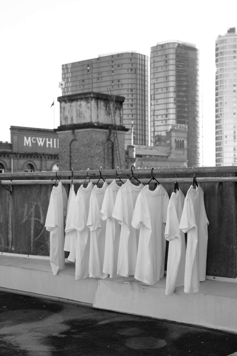 white t-shirts hanging on a rack in a city